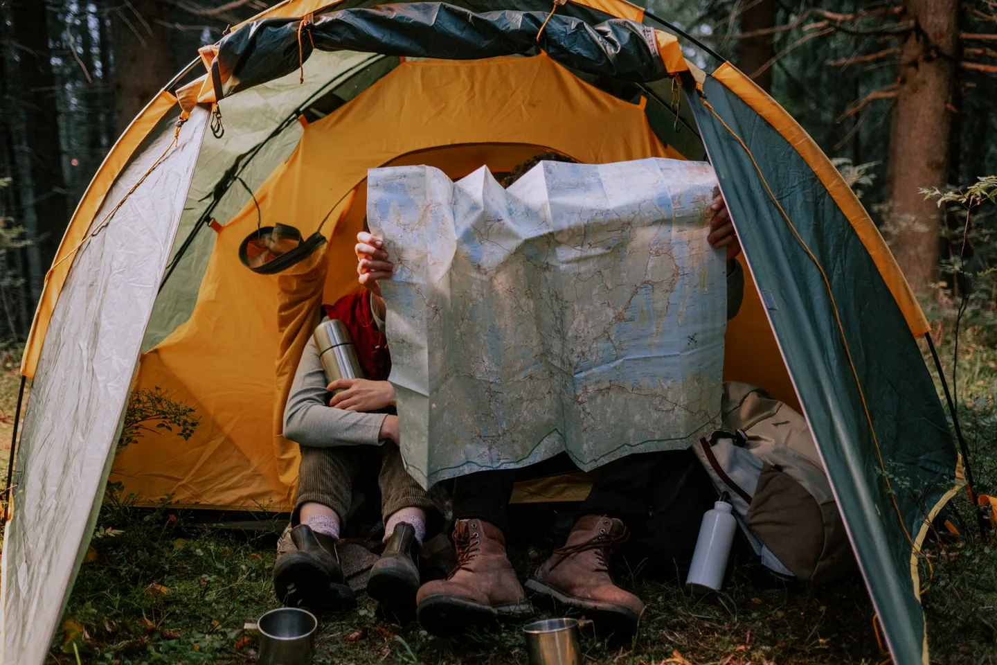 Two campers studying a large paper map in a tent