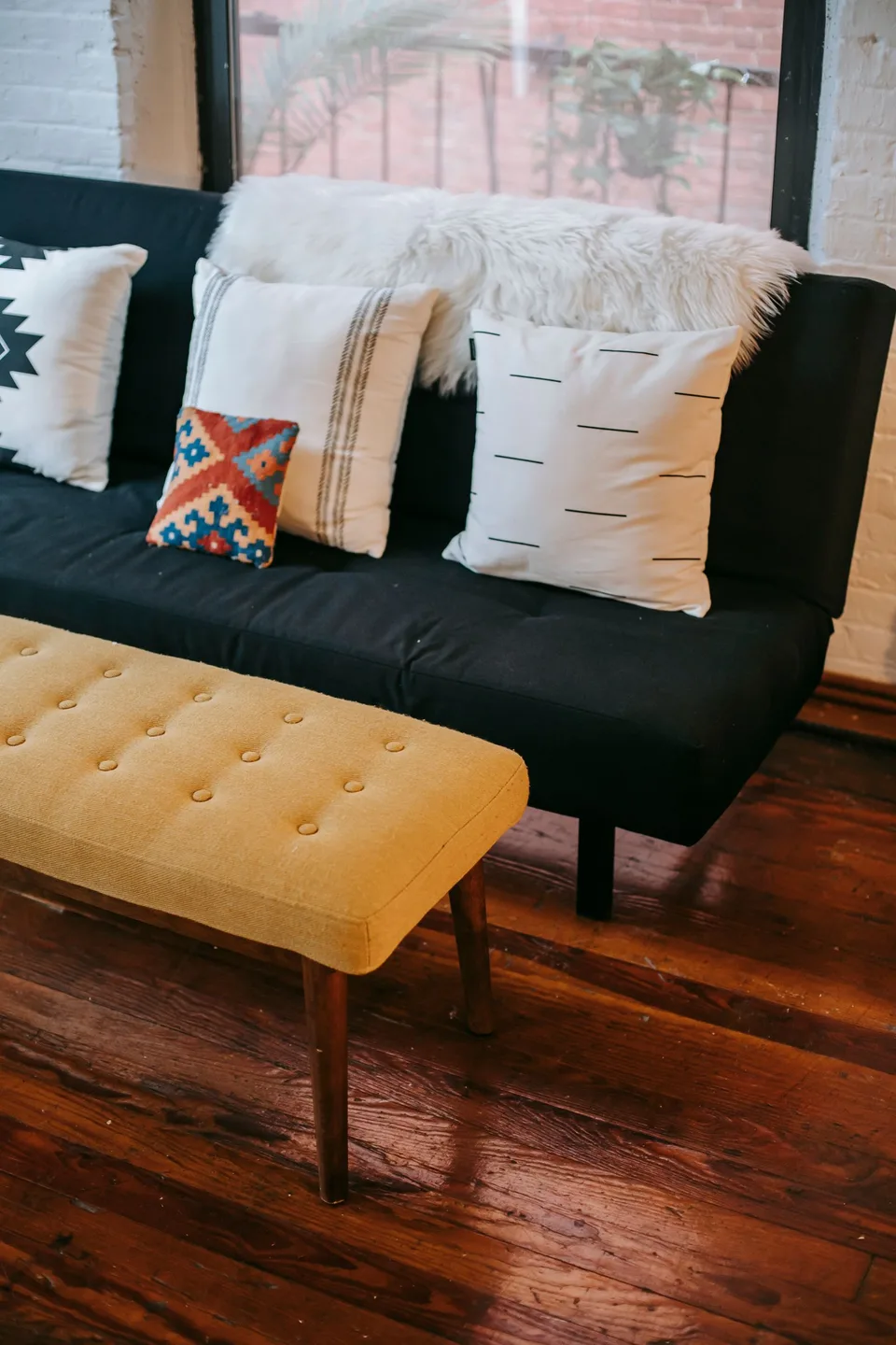 A sofa with patterned cushions and a yellow footstool